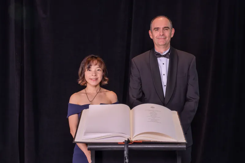 Chia-Hua Wu and Prof Alan Davidson standing in front of the book with the names of the indcutees to the Chancellor's Circle 2024.